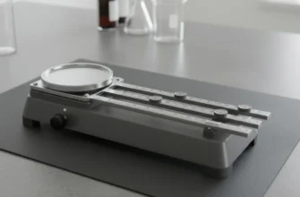 Close-up of a triple beam balance in a laboratory, showing the weighing pan, riders, and pointer scale for precise mass measurement