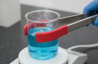 Stainless steel beaker tongs gripping a glass beaker on a hot plate